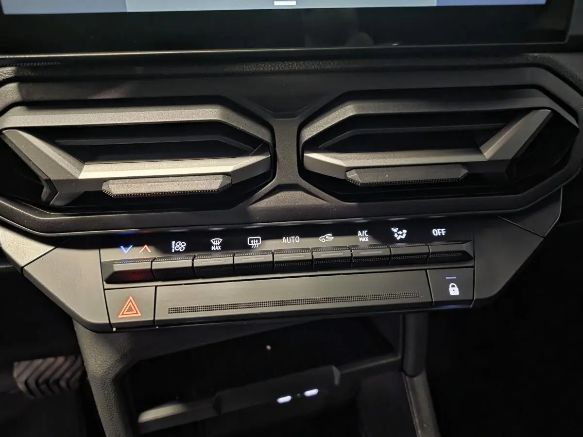 Détail des aérateurs gris acier et des commandes de climatisation du tableau de bord du Dacia Duster noir 2025.