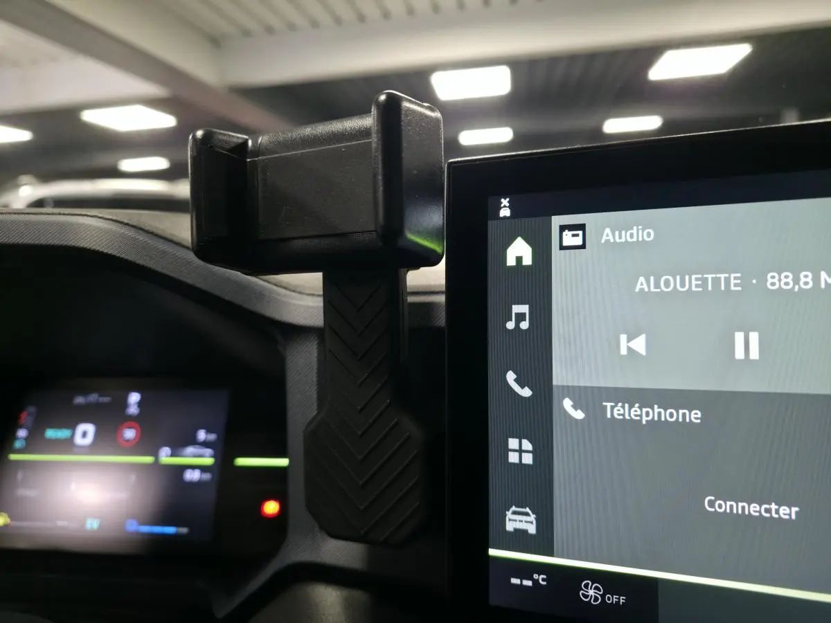 Vue intérieure rapprochée du tableau de bord du Dacia Duster 1.6 Hybrid 2025 avec support smartphone et écran tactile.