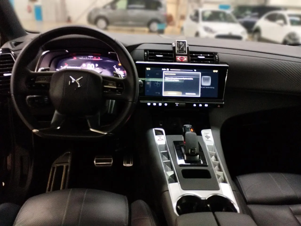 Vue intérieure du tableau de bord et console centrale du DS7 noir avec écran tactile et volant cuir noir.