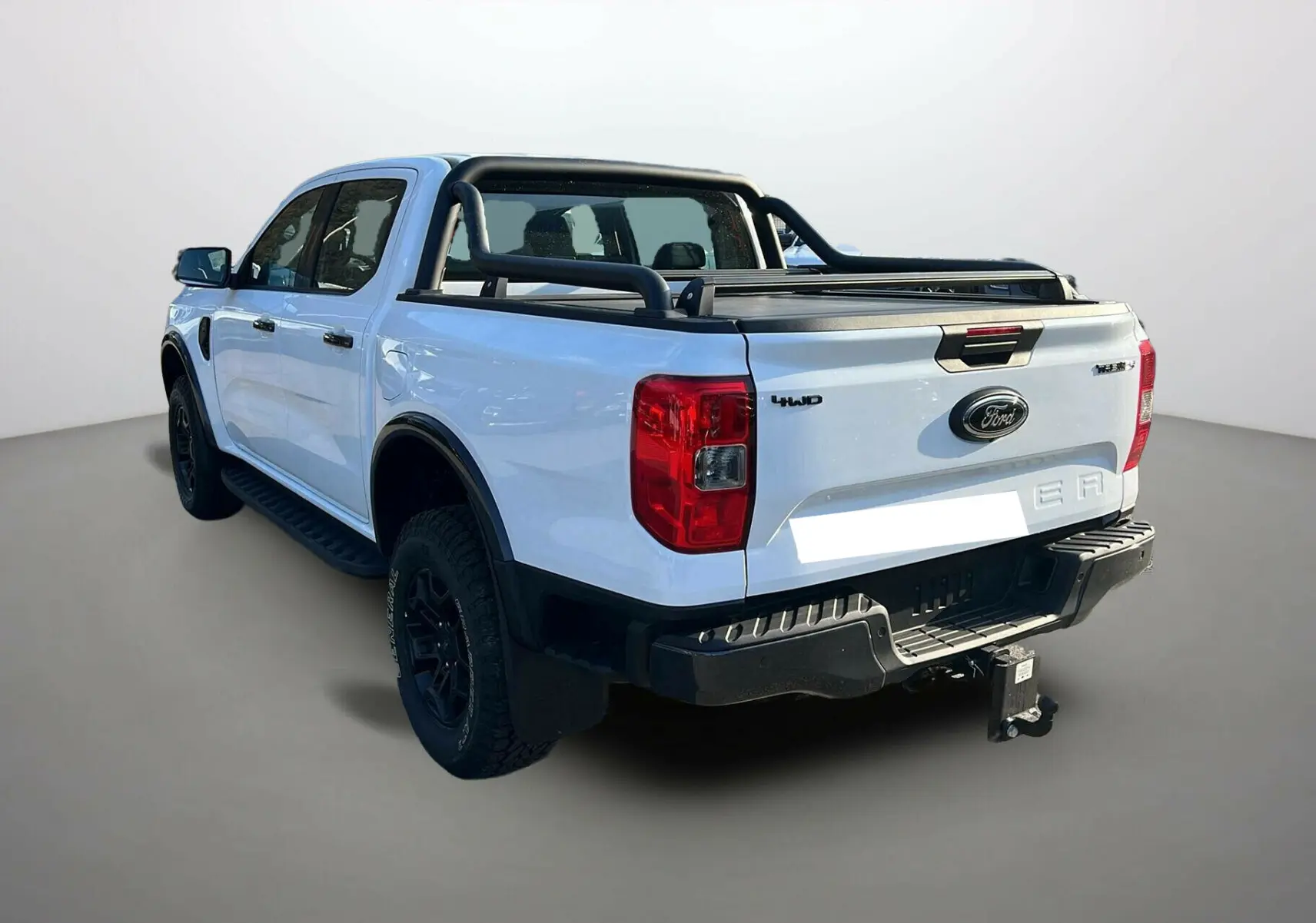 Ford Ranger blanc glacier en 3/4 arrière droit, avec arceaux noirs, attelage et benne couverte.