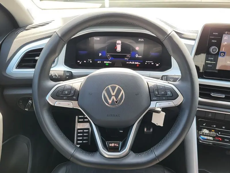 Vue rapprochée du volant multifonction noir du Volkswagen T-Roc 2025 avec tableau de bord numérique et écran central.