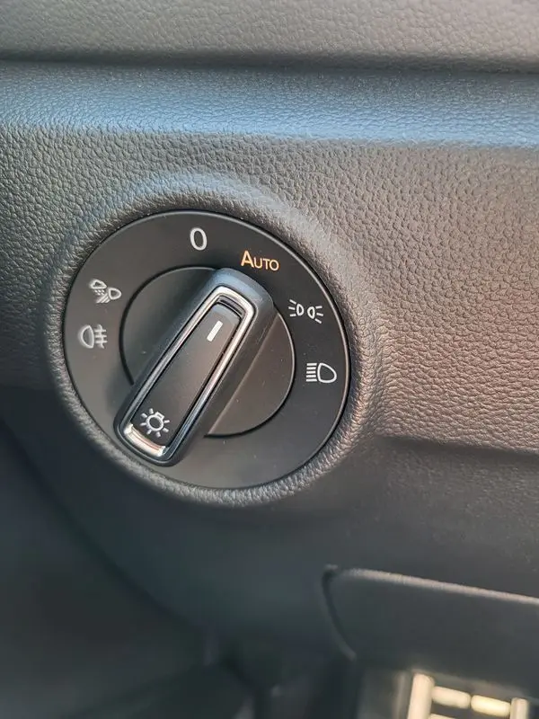 Gros plan sur le bouton de commande des phares du Volkswagen T-Roc gris Indium, avec réglage en mode automatique visible.