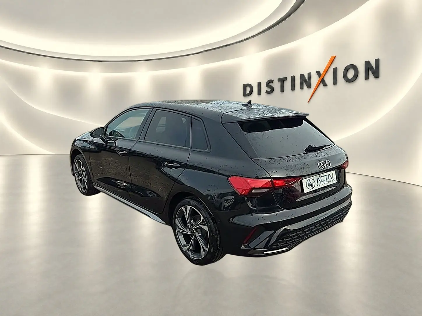 Audi A3 Sportback noir mythos vue 3/4 arrière droit avec jantes alu gris graphite dans un showroom lumineux.