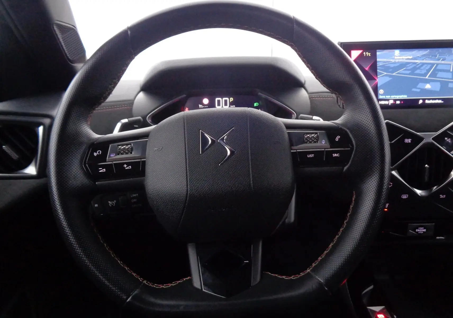 Volant en cuir noir avec logo DS au centre, tableau de bord numérique et écran tactile de navigation visible à droite.