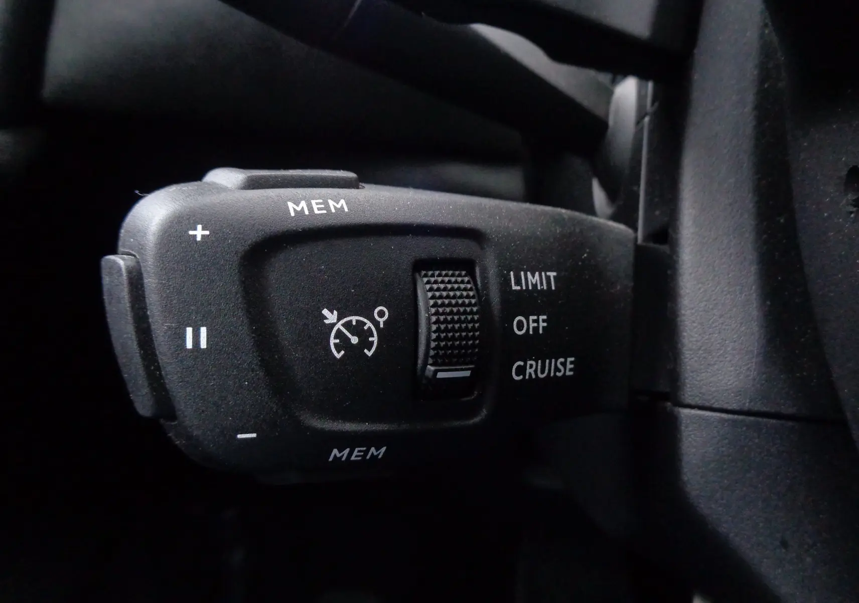 Gros plan sur la commande de régulateur de vitesse noire du DS3 Crossback gris platinium, côté gauche du volant.