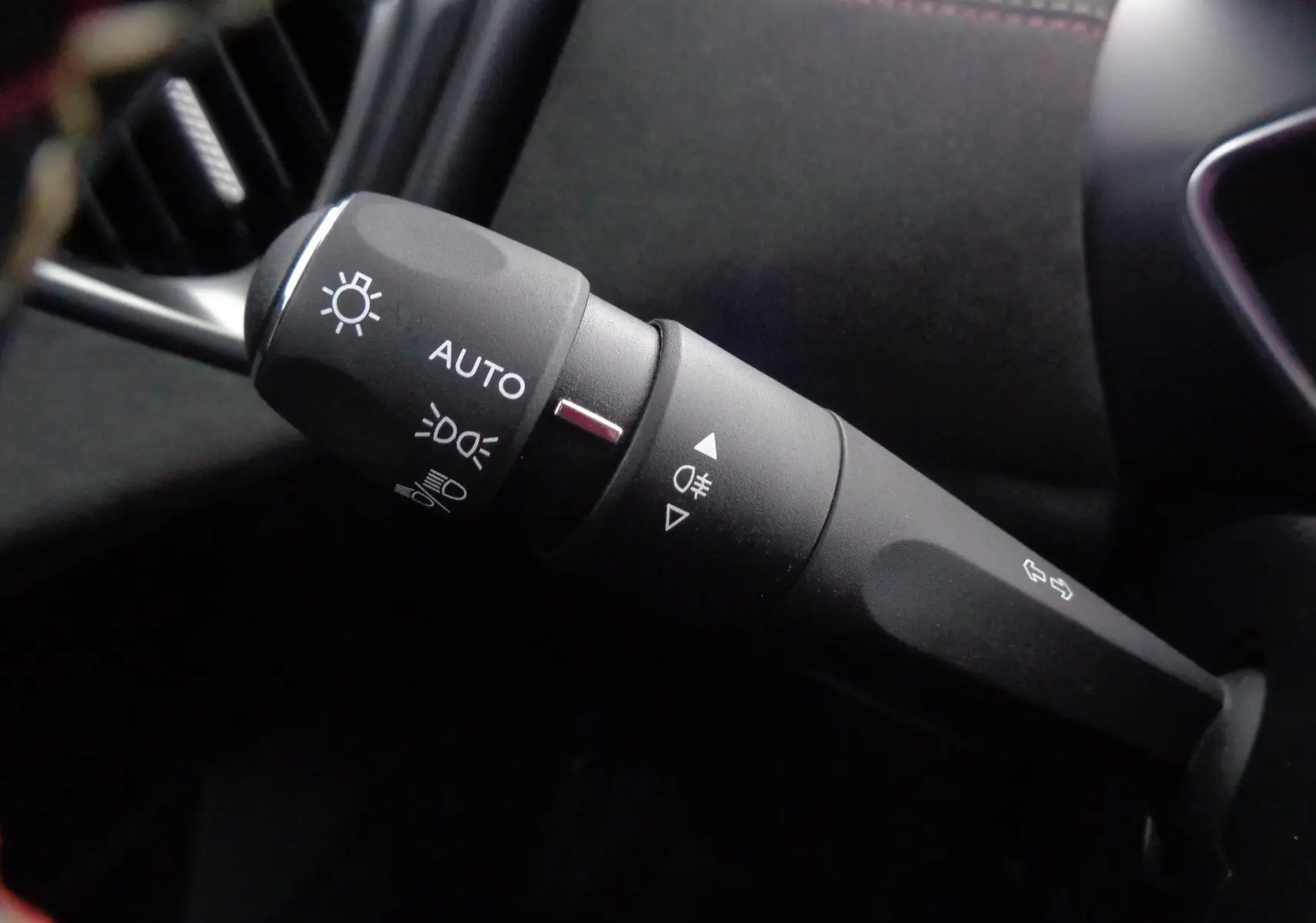 Gros plan sur la commande des phares et clignotants à gauche du volant dans l'habitacle noir du DS3 Crossback gris platinium.