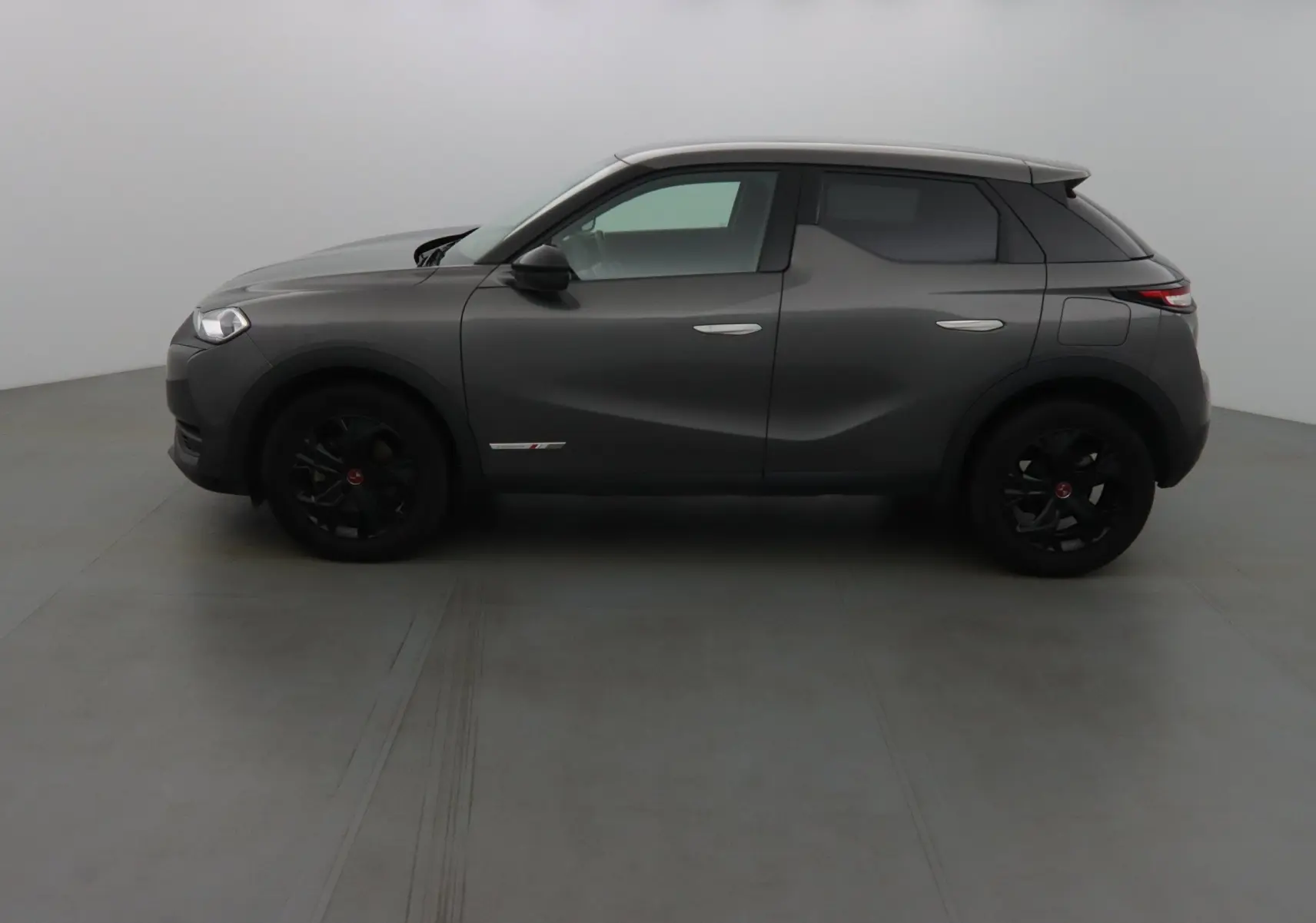 Profil côté gauche du DS3 Crossback gris platinium métallisé avec jantes noires et lignes sculptées visibles.