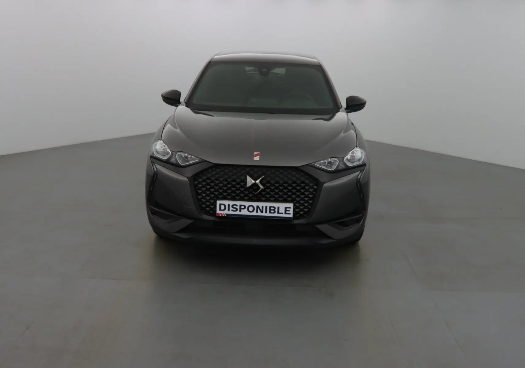 Vue frontale d'un DS3 Crossback gris platinium métal avec calandre noire et phares LED allumés.