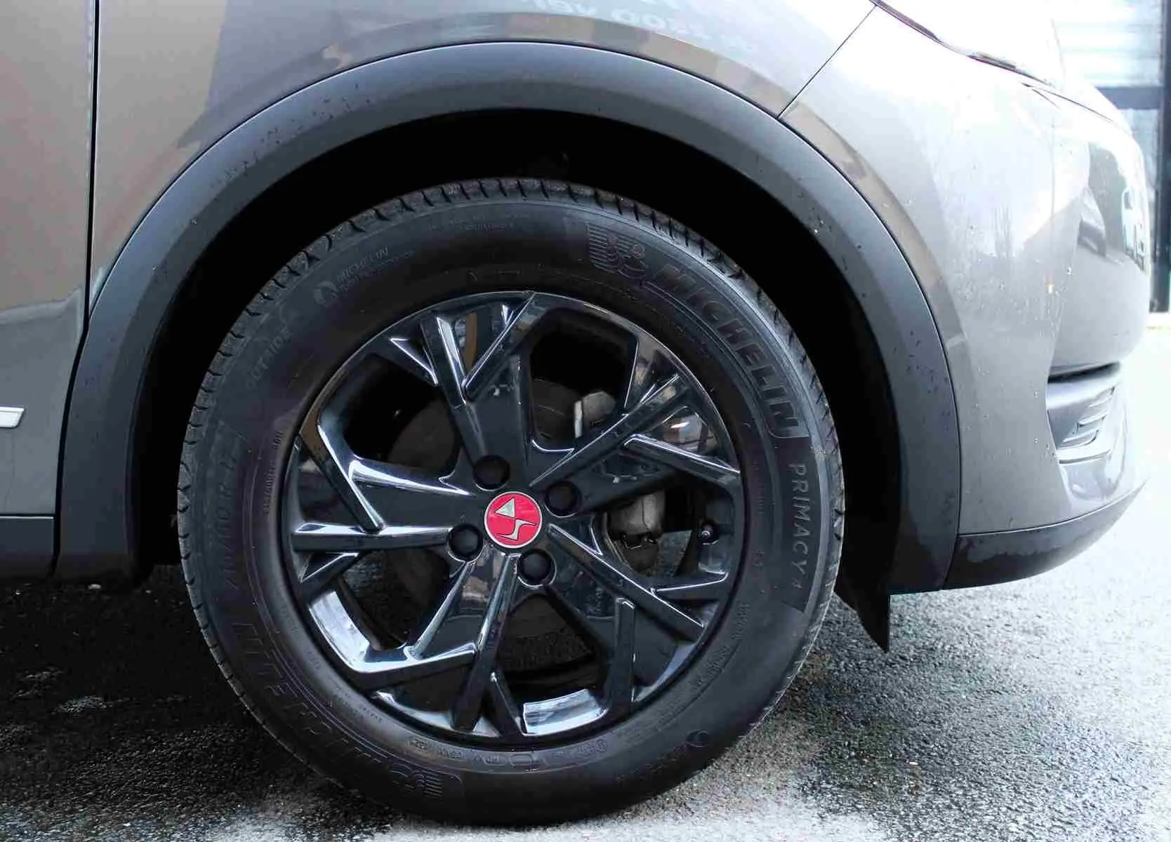 Gros plan sur la roue avant droite d’un DS3 Crossback gris platinium métal avec jante noire brillante et logo rouge central.