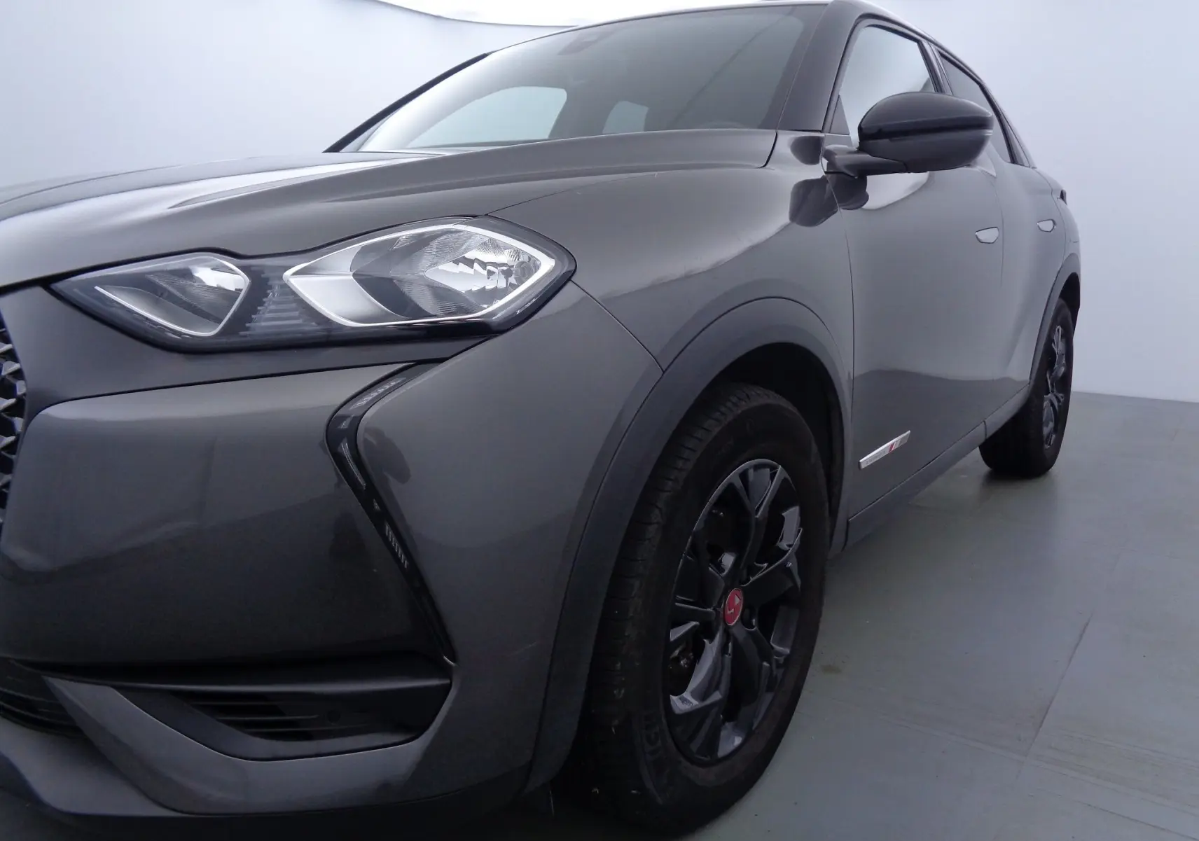 Vue 3/4 avant droit d'un DS3 Crossback gris platinium métal avec jantes noires et phares LED distinctifs.