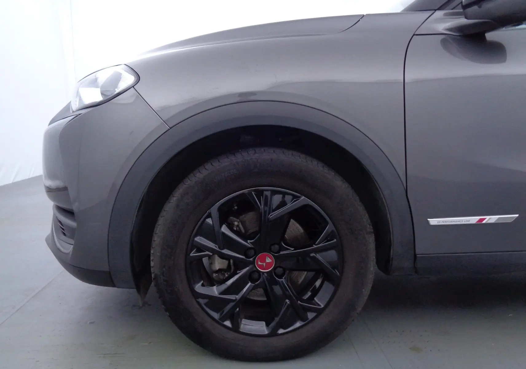 Vue latérale côté avant gauche du DS3 Crossback gris platinium métal avec jante noire et badge Performance Line sur la porte.