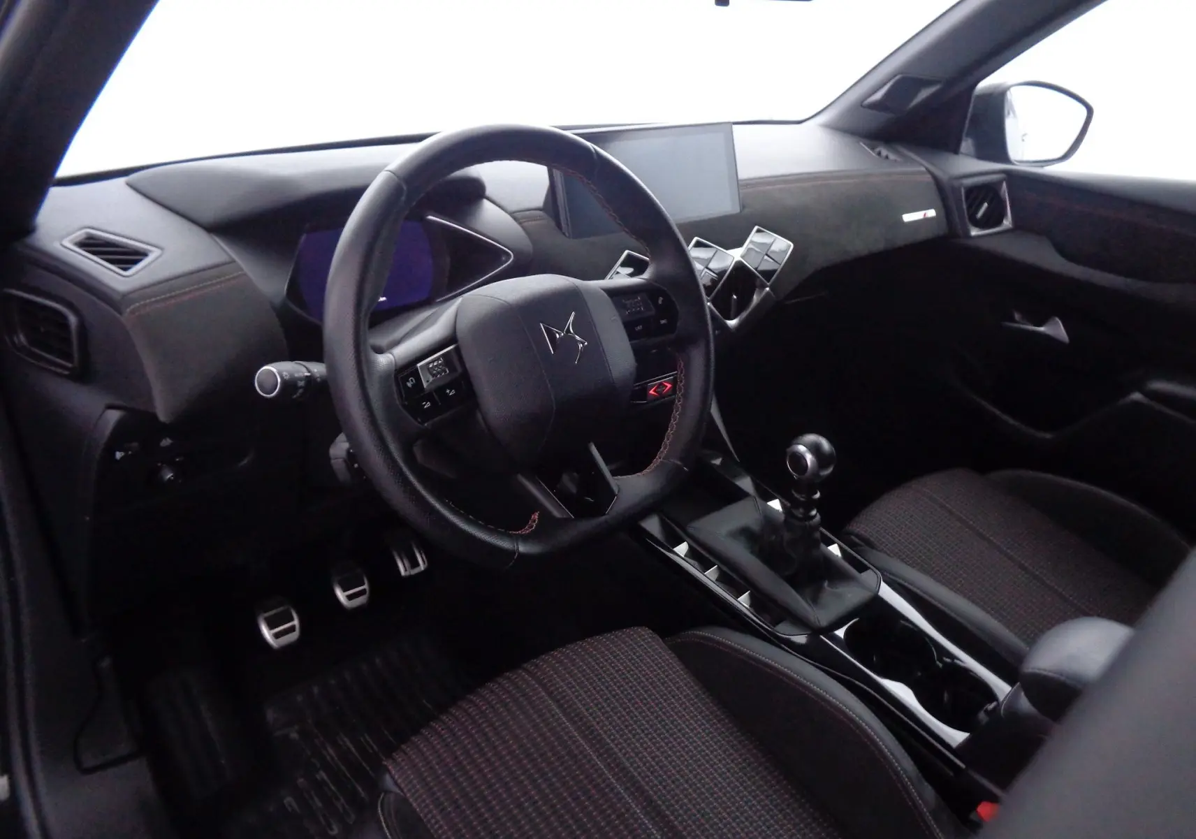 Vue intérieure côté conducteur du DS3 Crossback 2021, volant cuir noir, console centrale avec levier de vitesses manuel.