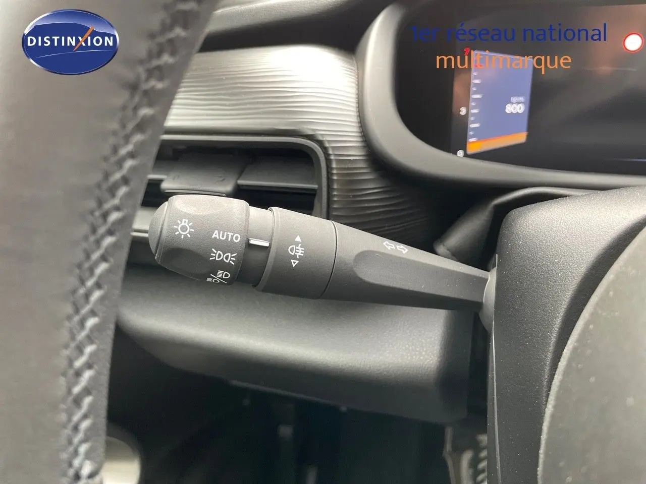 Gros plan sur la manette des feux et clignotants à gauche du volant dans l'habitacle du Jeep Avenger blanc neige 2024.