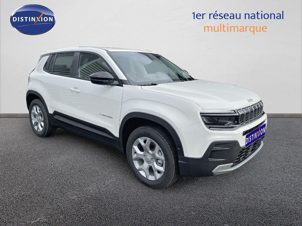 Jeep Avenger blanc neige vu en 3/4 avant droit, avec calandre noire et jantes argentées sur fond neutre.