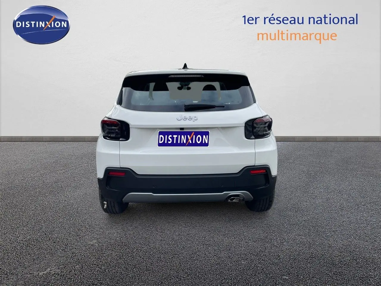 Vue arrière d'un Jeep Avenger blanc neige 2024 avec feux arrière fumés et une sortie d'échappement visible côté droit.