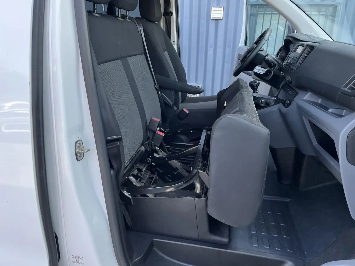 Vue intérieure côté gauche du Toyota Proace Fourgon blanc 2021, siège passager avant relevé montrant la structure métallique.