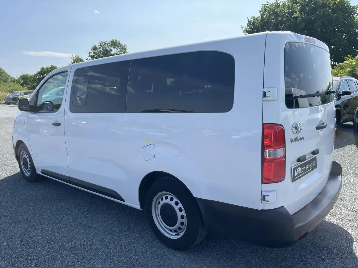 Vue 3/4 arrière droite d'un Toyota Proace Fourgon blanc avec vitres arrière teintées et pare-chocs noirs.