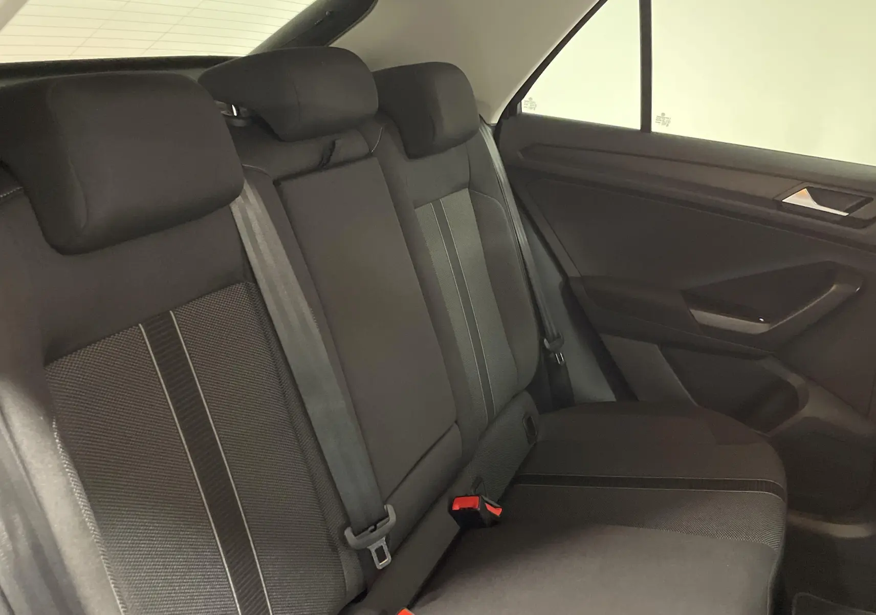 Banquette arrière en tissu noir avec appuie-têtes et ceintures visibles dans un Volkswagen T-Roc 2024.