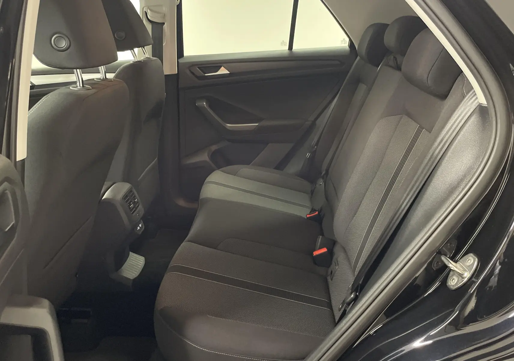 Vue intérieure côté droit des sièges arrière noirs du Volkswagen T-Roc 1.5 TSI 2024 avec tissu et ceintures visibles.