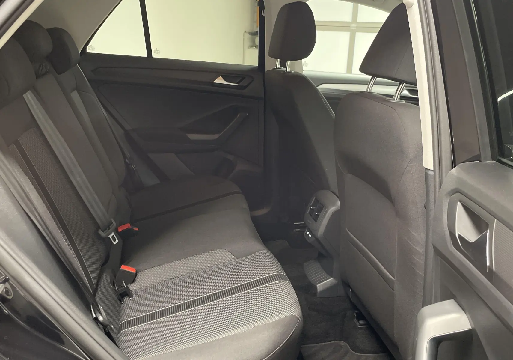 Vue intérieure côté gauche sur les sièges arrière noirs du Volkswagen T-Roc 2024 avec portières ouvertes.