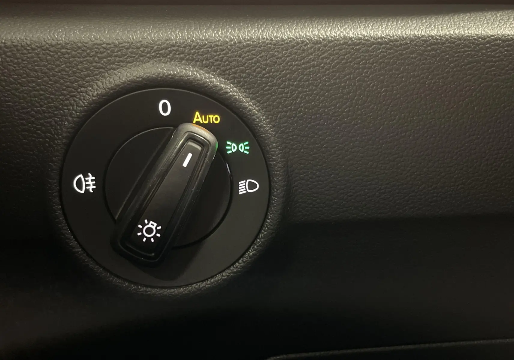 Gros plan sur le sélecteur de phares du Volkswagen T-Roc 2024, finition Noir Intense nacré, avec mode automatique activé.