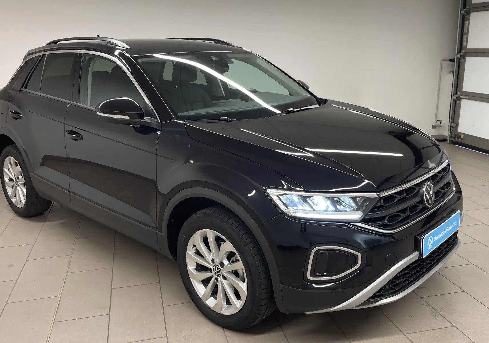Volkswagen T-Roc 1.5 TSI noir nacré en 3/4 avant droit avec jantes alliage 17'' Johannesburg et phares allumés.