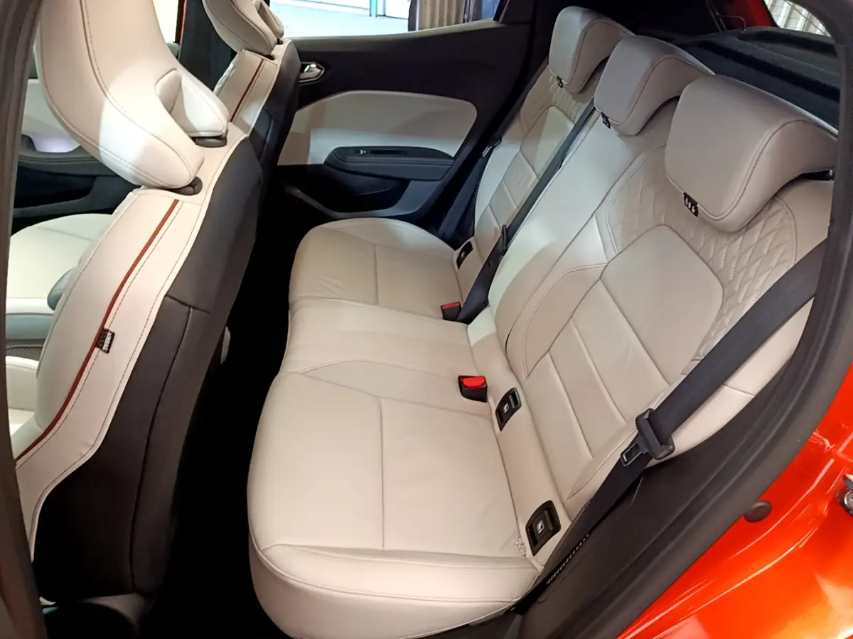 Vue côté droit de la banquette arrière beige clair de la Renault Clio Initiale Paris orange, avec finitions élégantes et ceintures noires.