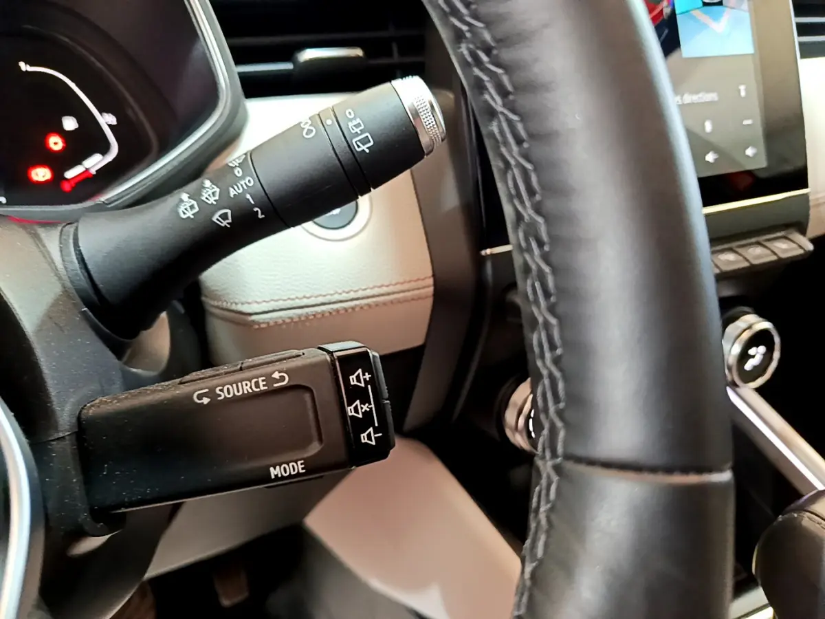 Gros plan sur la commande multimédia et le volant en cuir noir de la Renault Clio Initiale Paris orange 2021.