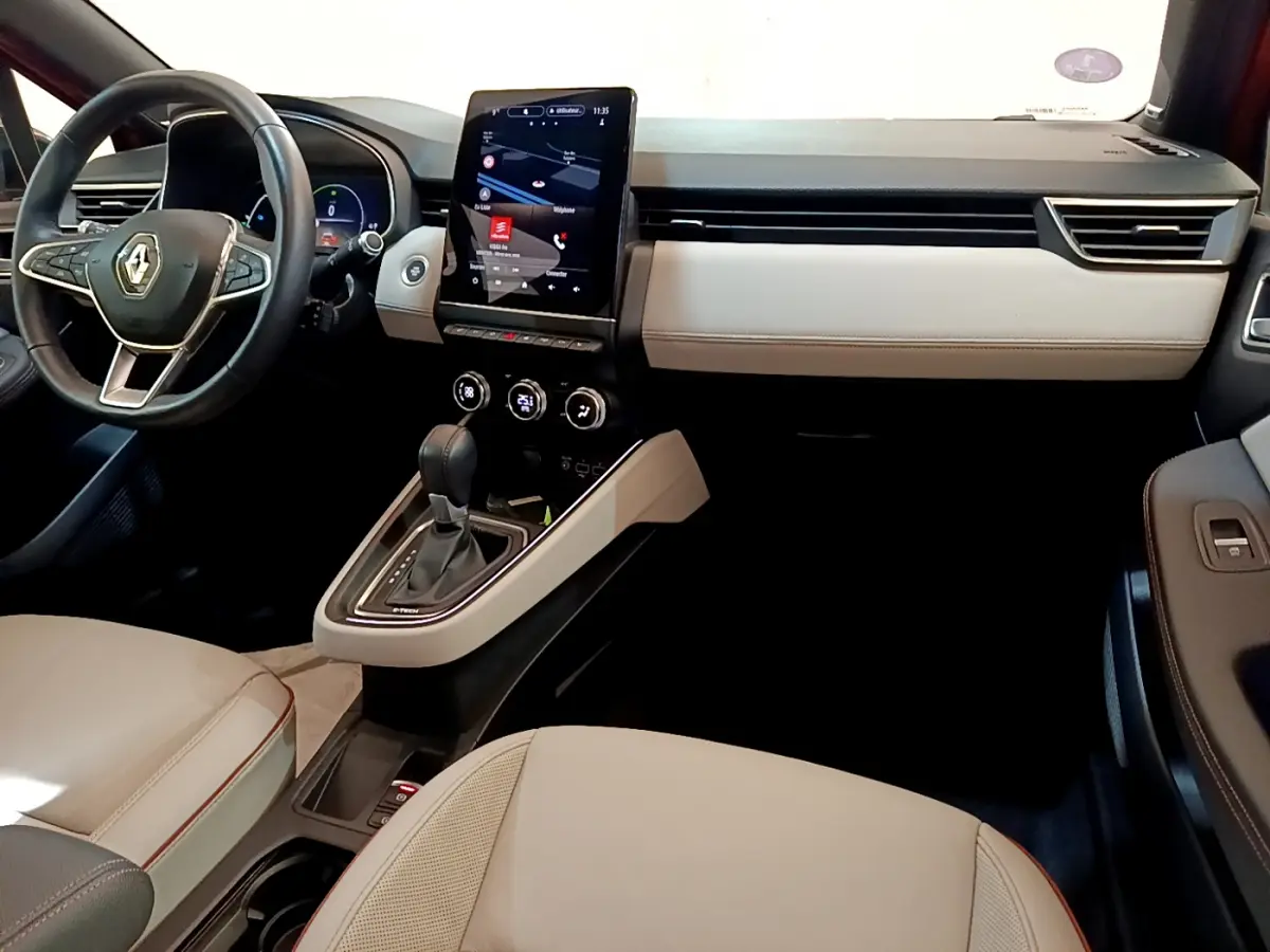 Intérieur de la Renault Clio Initiale Paris E-TECH 140, vue côté conducteur, tableau de bord beige et noir avec écran tactile vertical.