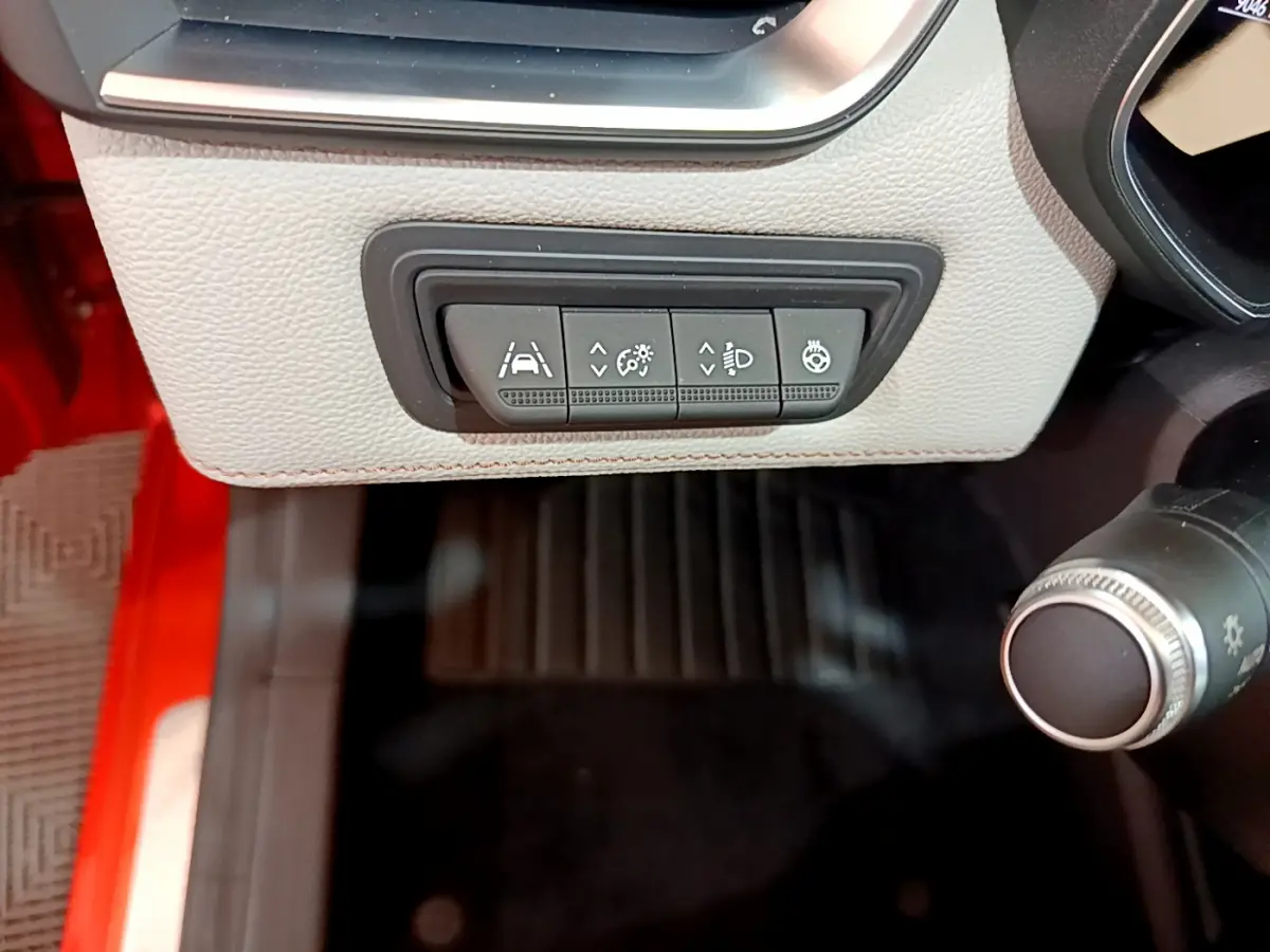 Gros plan sur les commandes d'assistance et éclairage à gauche du volant dans l'habitacle d'une Renault Clio orange 2021.