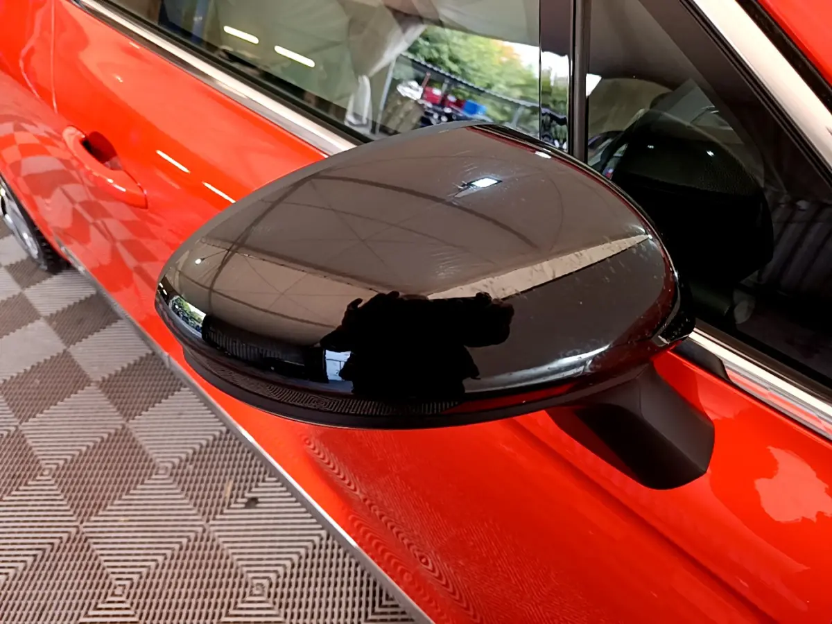 Rétroviseur noir côté gauche sur porte orange vif d'une Renault Clio Initiale Paris E-TECH 2021 vue rapprochée.