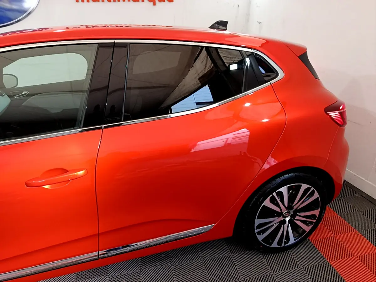 Profil côté gauche de la Renault Clio Initiale Paris orange 2021, mettant en valeur la jante alliage et les vitres teintées.