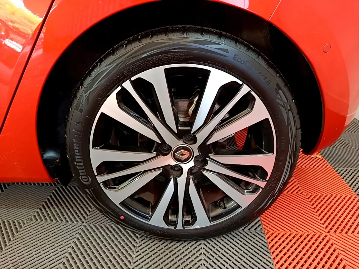 Gros plan sur la roue avant droite orange d'une Renault Clio Initiale Paris E-TECH 140 avec jante alliage bicolore