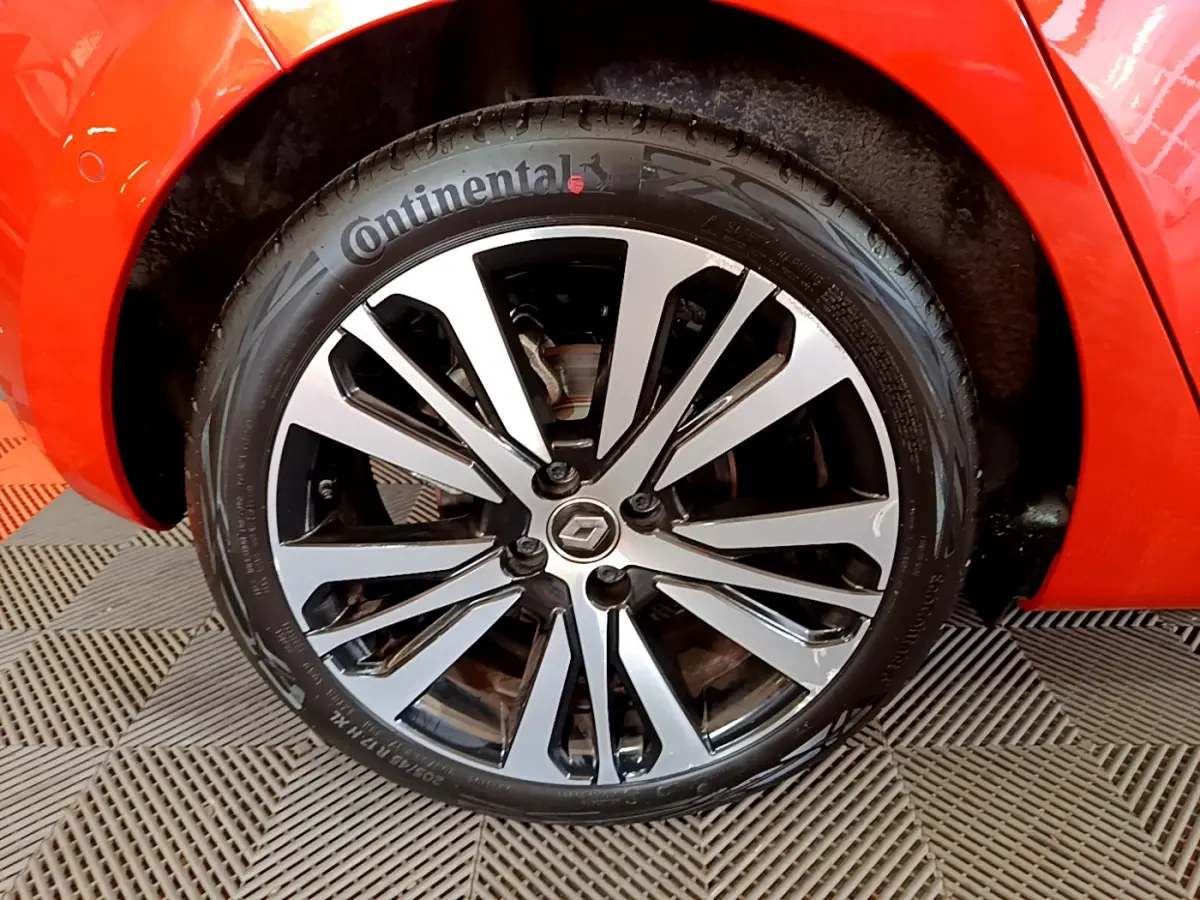 Gros plan sur la roue avant gauche de la Renault Clio orange, mettant en valeur la jante alliage et le pneu Continental.