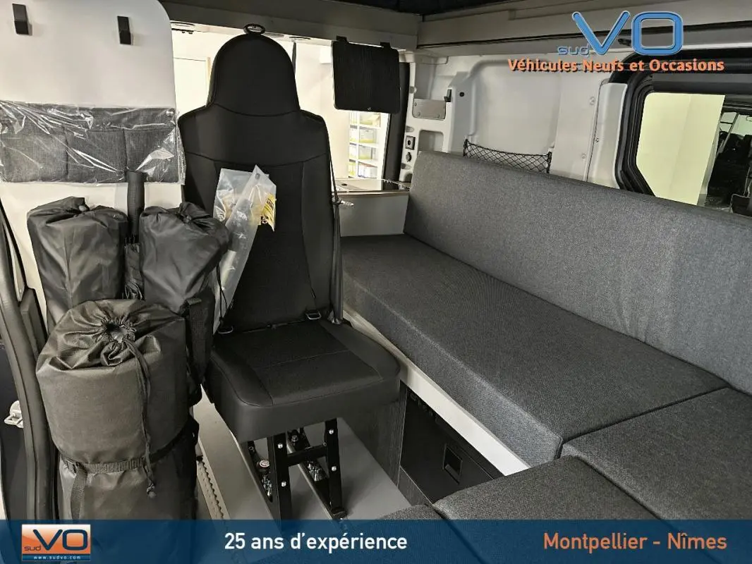 Intérieur du Renault Trafic Fourgon gris 2025 montrant siège avant et banquette latérale en tissu gris.
