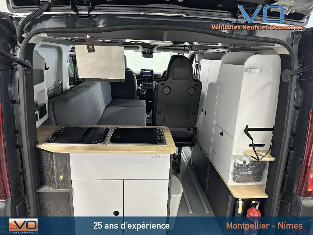 Vue arrière intérieure du Renault Trafic Fourgon gris 2025 aménagé avec kitchenette et banquette côté gauche.