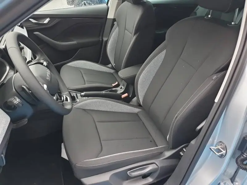 Vue intérieure côté conducteur du Skoda Kamiq 2025, sièges tissu noir et gris avec accoudoir central.