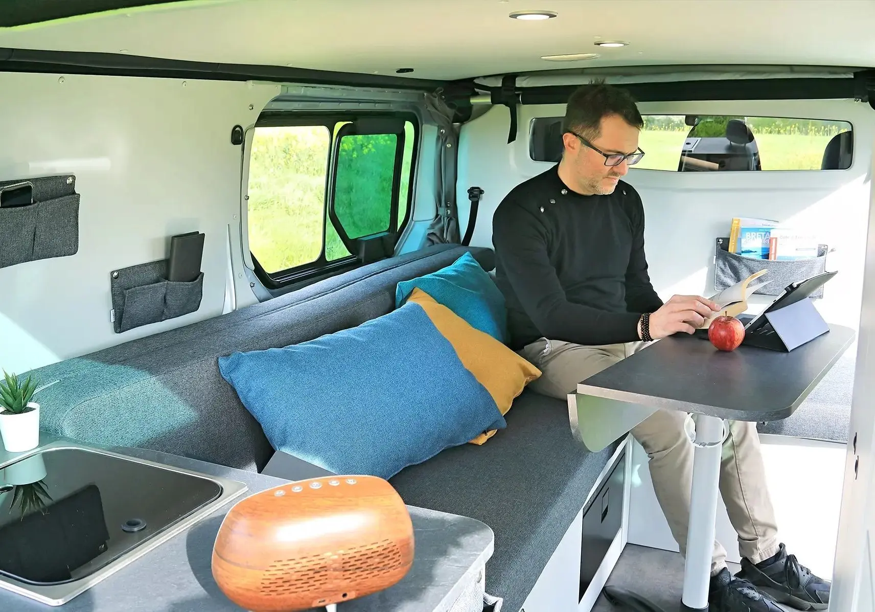 Intérieur du Renault Trafic Fourgon gris platine, vue latérale montrant banquette, table et aménagement compact.