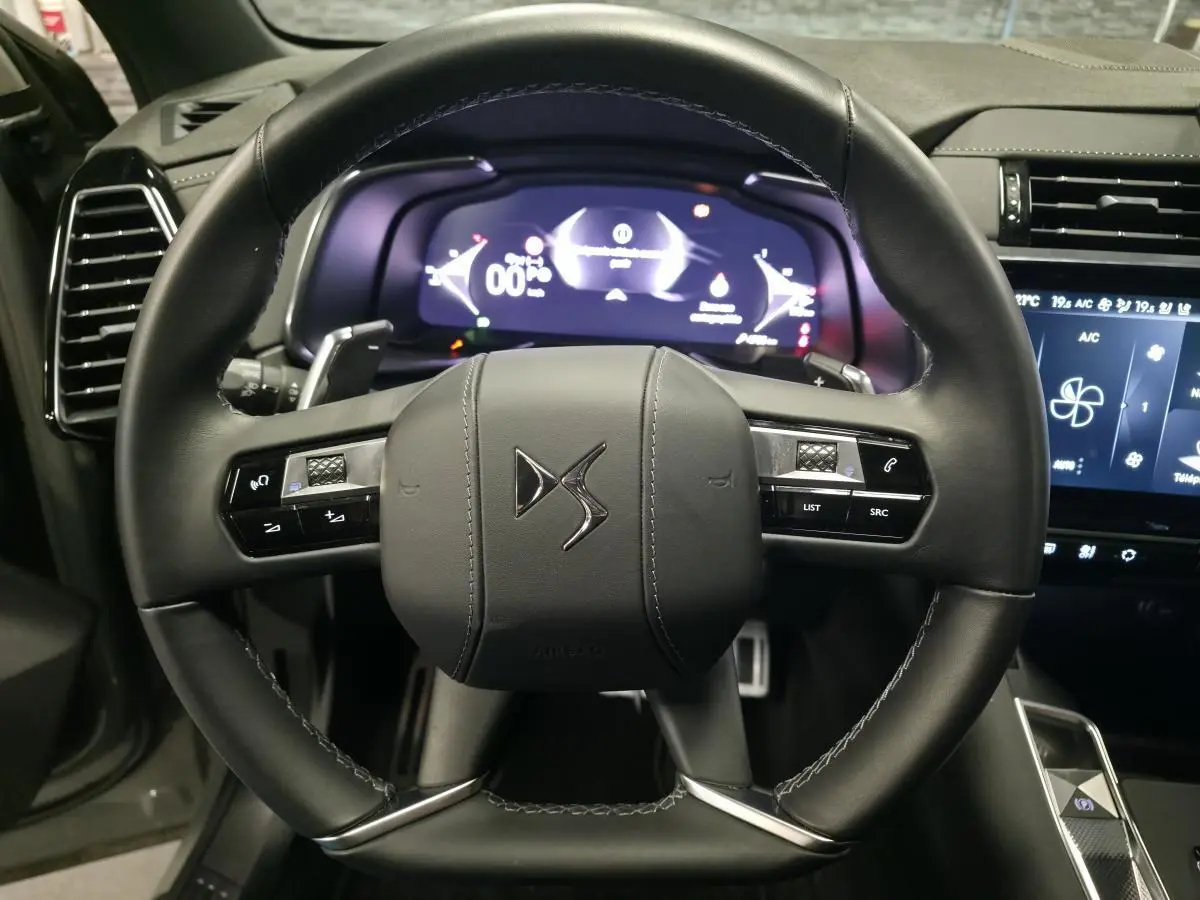Vue rapprochée du volant en cuir noir du DS7 Crossback 2025 avec commandes intégrées et tableau de bord numérique.