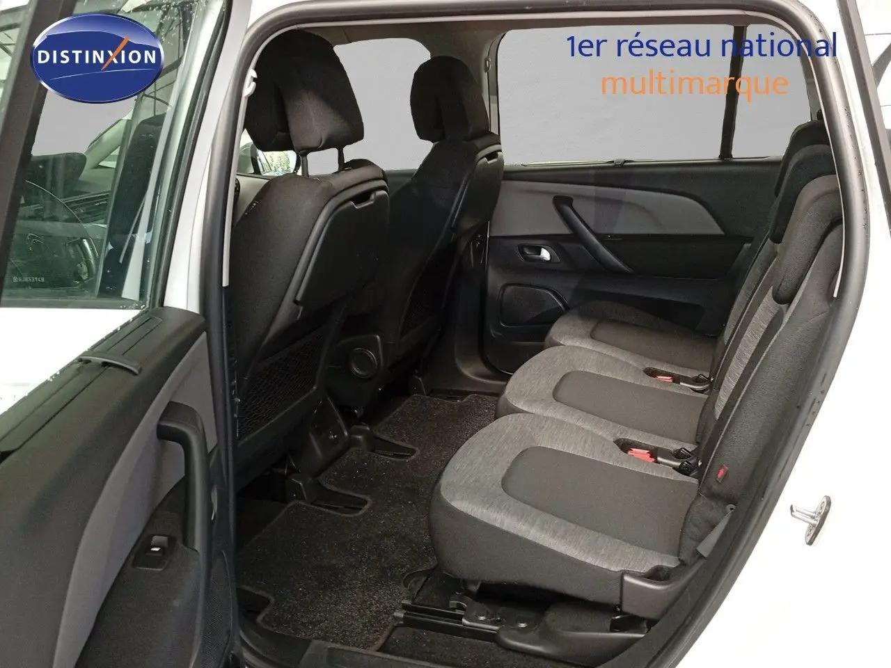 Vue intérieure côté droit sur les sièges arrière gris du Citroën Grand C4 Picasso blanc avec porte ouverte.