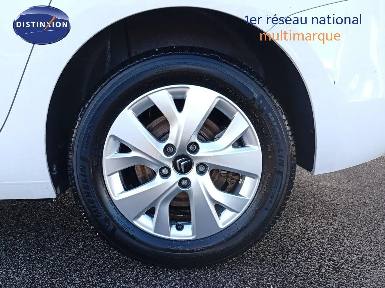 Gros plan sur la roue avant gauche blanche d'un Citroën Grand C4 Picasso II avec jante alliage et pneu Michelin.