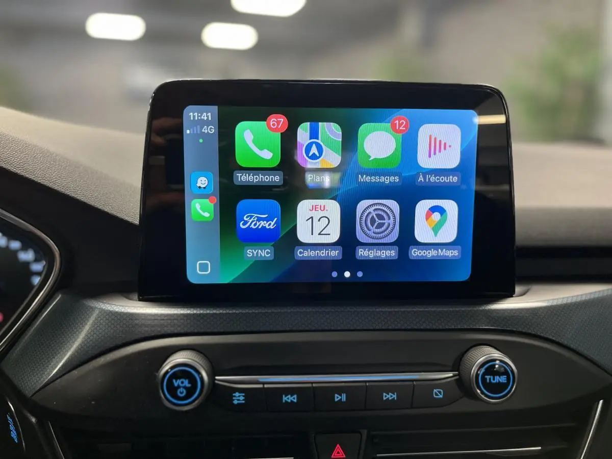 Écran tactile central du Ford Focus 2021 affichant l'interface Apple CarPlay avec commandes audio en dessous.