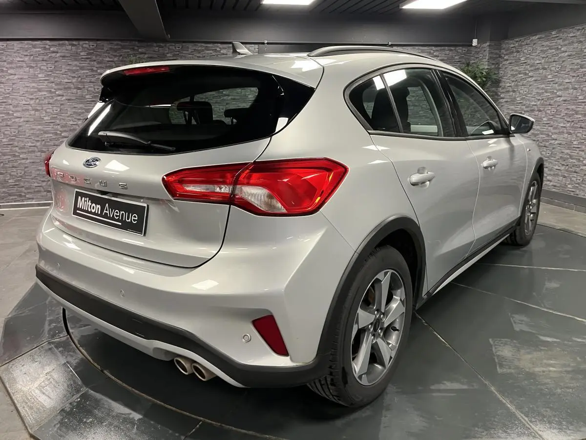 Vue 3/4 arrière droite d'une Ford Focus gris lunaire 2021 avec double sortie d'échappement et jantes alliage 17 pouces.