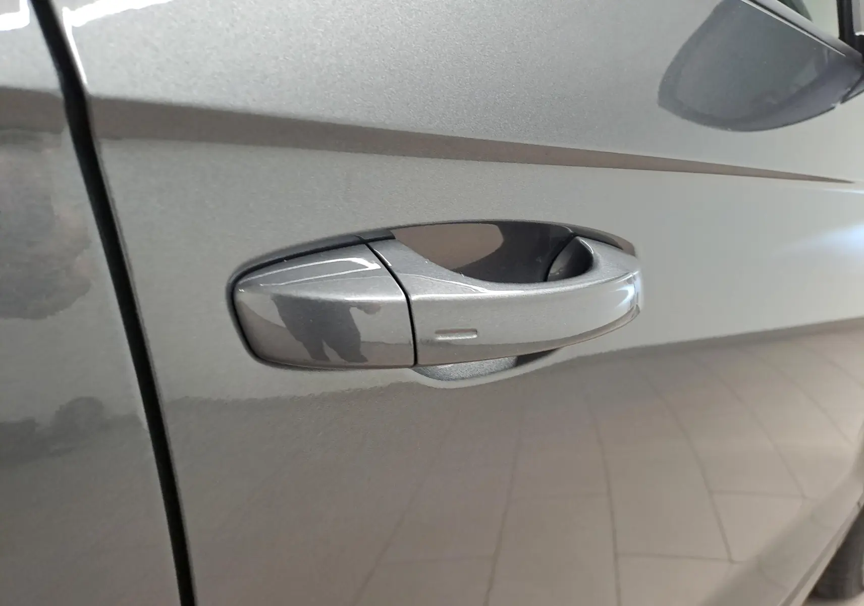 Poignée de porte côté gauche du Volkswagen T-Roc 2024 gris Indium avec peinture métallisée visible en gros plan.