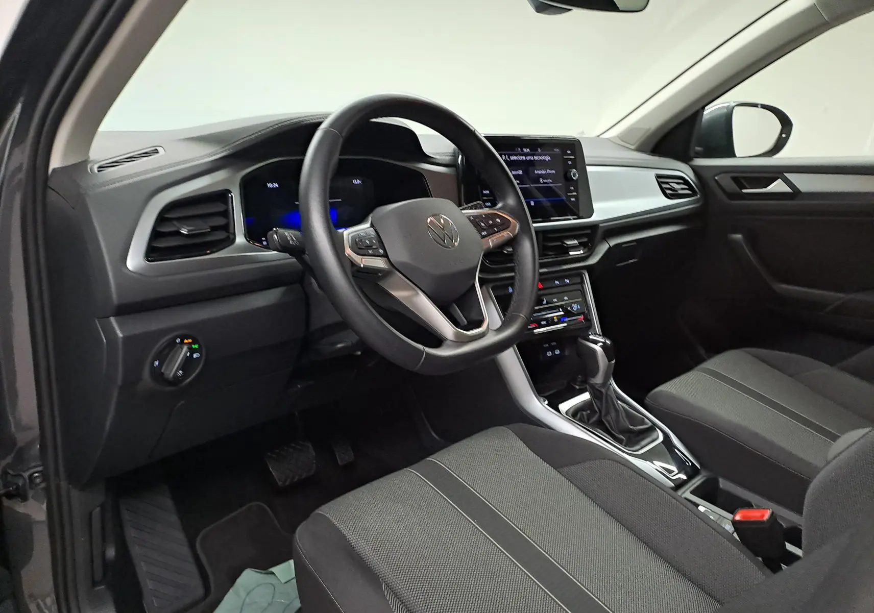 Intérieur côté conducteur du Volkswagen T-Roc 2024 gris Indium, avec tableau de bord numérique et écran tactile central.