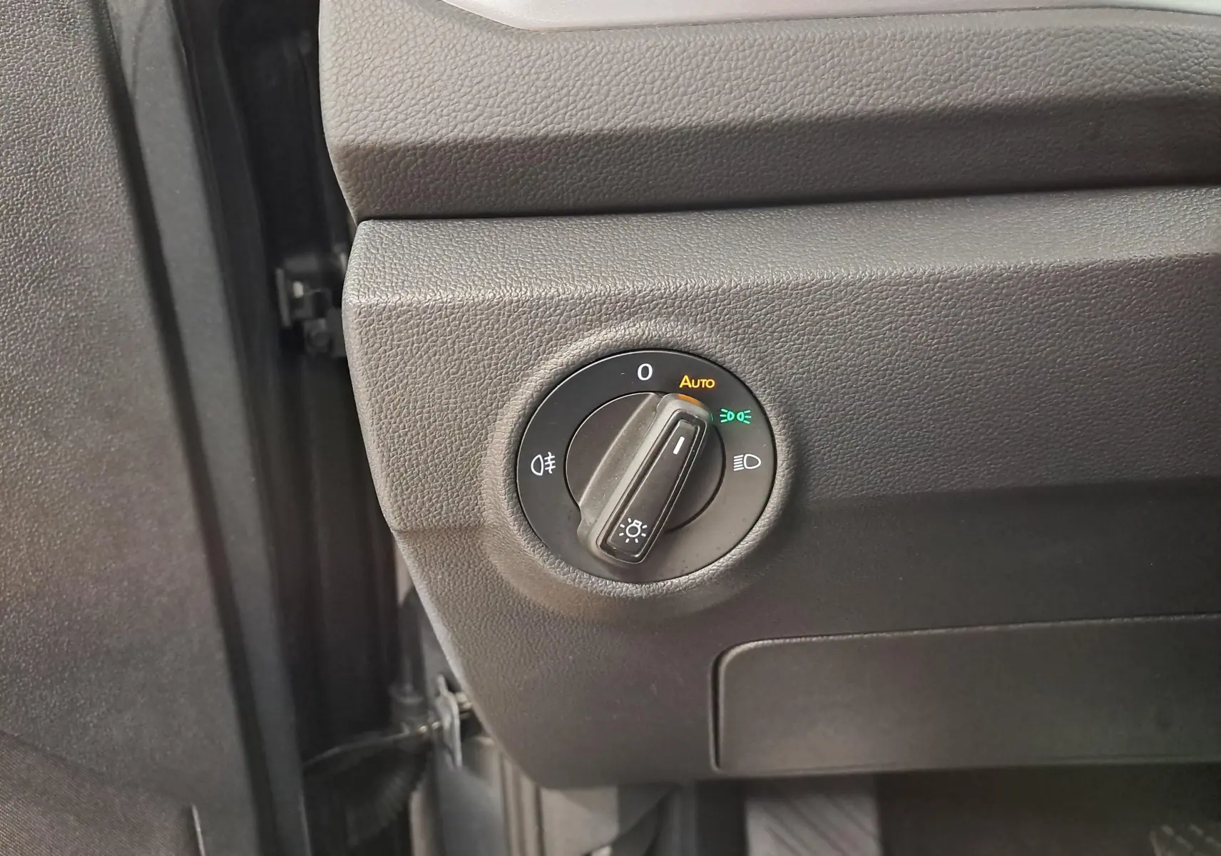 Gros plan sur le bouton de commande des phares du Volkswagen T-Roc 2024, intérieur noir texturé.