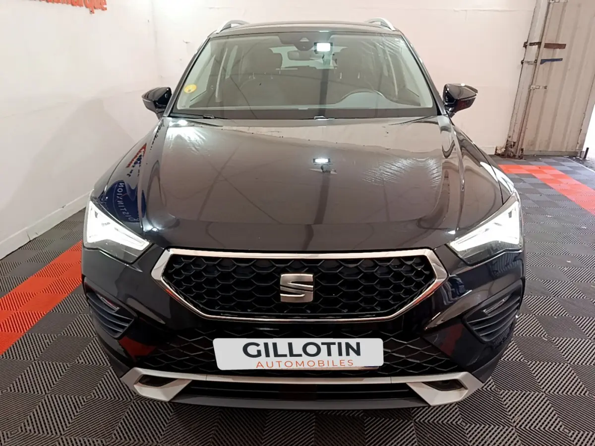 Vue de face d'un SEAT Ateca noir 2022 avec calandre hexagonale et phares LED allumés dans un garage.