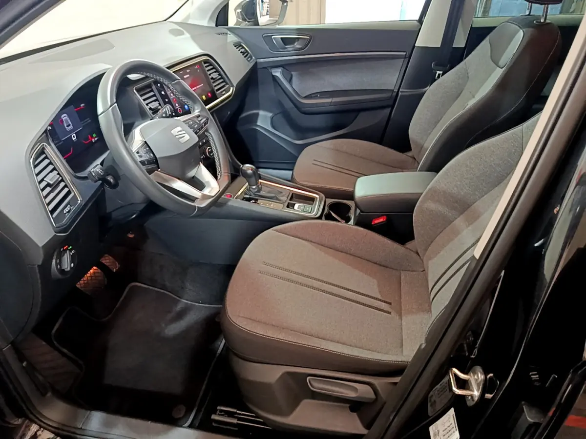 Intérieur avant droit du SEAT Ateca 2022 noir, avec sièges tissu gris, volant multifonctions et écran tactile central.
