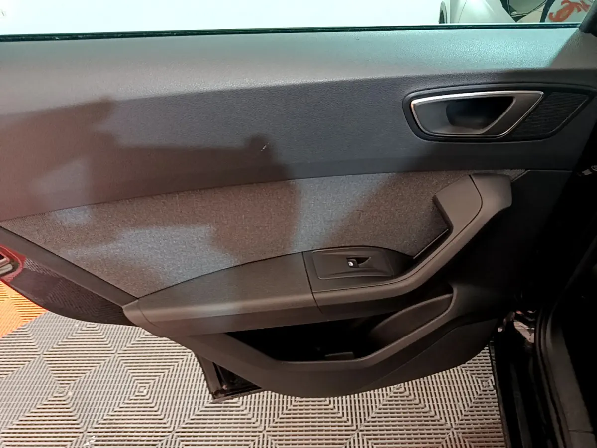 Intérieur côté gauche de la porte avant noire du SEAT Ateca 2022, avec poignée argentée et tissu gris.
