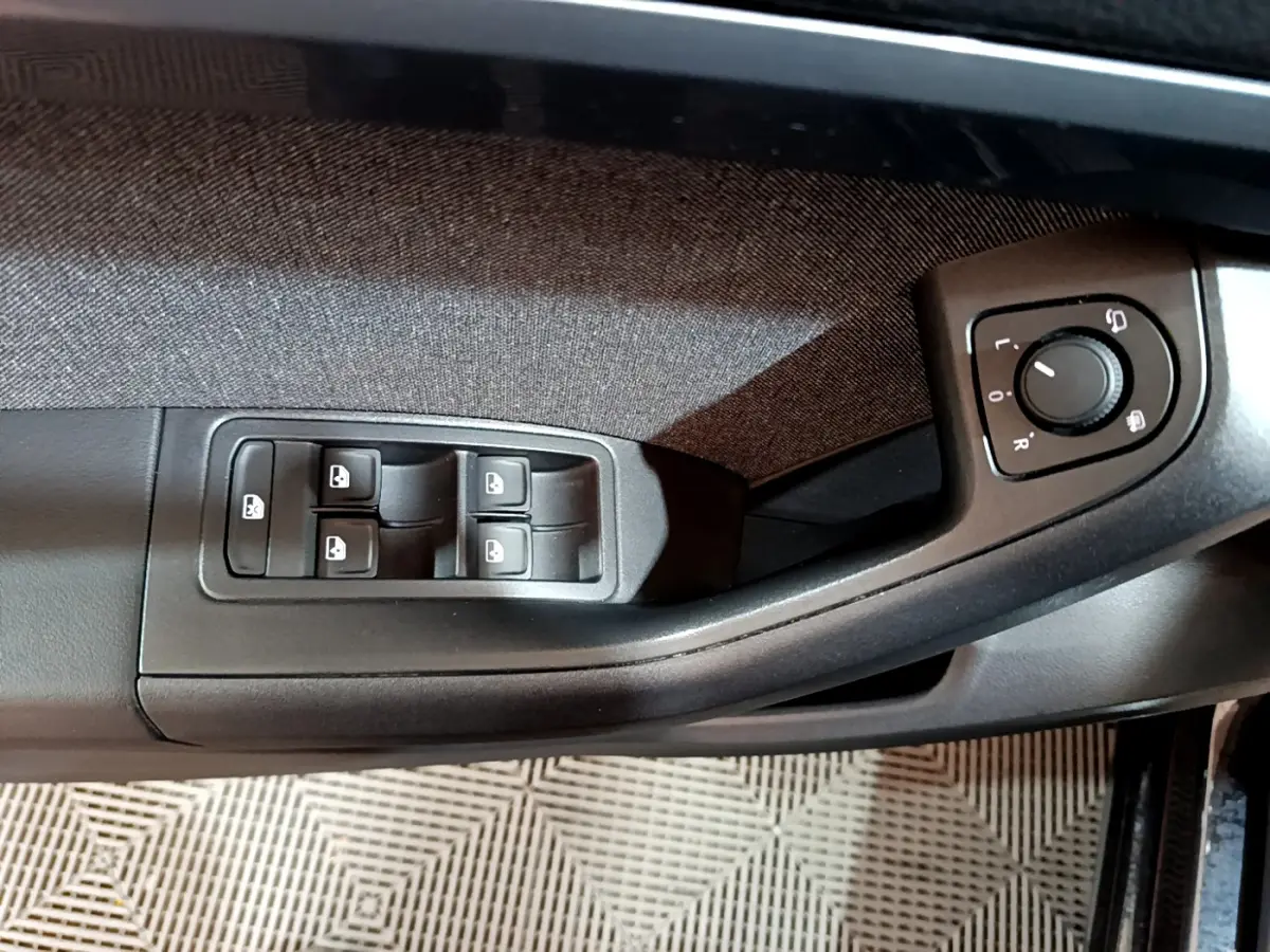 Vue rapprochée des commandes de lève-vitres et réglage des rétroviseurs côté conducteur d’un SEAT Ateca noir 2022.